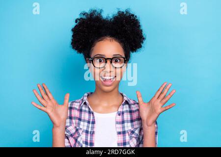 Portrait de la personne extatique surjoyée impressionnée avec la coiffure afro porter chemise à carreaux regardant la bouche ouverte isolée sur fond de couleur bleue Banque D'Images