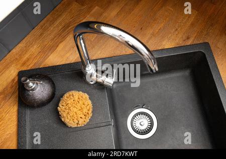 Utilisation de l'éponge de mer naturelle pour le lavage de la vaisselle dans le concept de cuisine à la maison. Éponge de mer récoltée bio sur l'évier de cuisine à côté du savon liquide lave-vaisselle. Banque D'Images