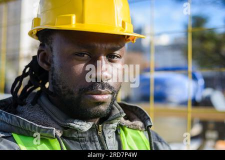 portrait d'un homme ingénieur barbu noir, portant un casque de sécurité surveillant la caméra debout à l'extérieur sur le chantier de construction, concept de l'industrie, c Banque D'Images
