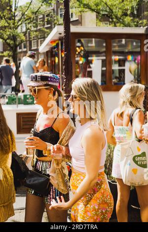 Amsterdam, Hollande du Nord, pays-Bas – 6 août 2022 : deux jeunes femmes célébrant la Pride Amsterdam marchent dans la rue en tenues colorées Banque D'Images