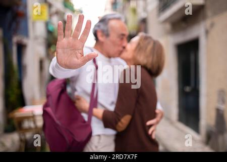 Amoureux Senior couple s'embrassant de faire un geste d'arrêt à la caméra en plein air Banque D'Images