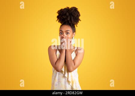 Choqué jeune femme noire effrayée en robe couvrant la bouche avec les mains Banque D'Images