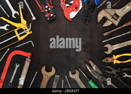 Composition à plat avec des instruments anciens et nouveaux sur un fond en bois sombre. Vue de dessus avec divers outils de réparation. Outils et espace vide pour le texte Banque D'Images