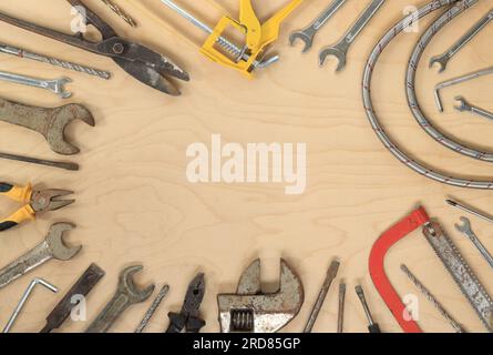 Outils pour différents travaux de réparation, vue de dessus. Vieux outils sur une table en bois clair, espace vide au centre Banque D'Images
