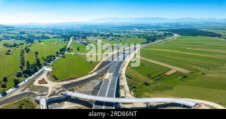 Nouveau fragment d'autoroute en construction sur la route de Zakopianka en Pologne, de Cracovie à Zakopane dégageant la ville de Nowy Targ, principal lieu des embouteillages. Banque D'Images