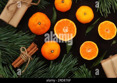 Noël, fond d'hiver du nouvel an avec des mandarines juteuses sur une table en bois sombre. Vue de dessus des agrumes, cadeaux, branches de pin et cannelle dans Banque D'Images