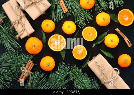 Noël, nouvel an fond lumineux d'hiver avec mandarines, vue de dessus. Mandarines sur une table en bois sombre, cadeaux, branches de pin et cannelle. Festiv Banque D'Images