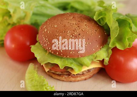 Cheeseburger avec côtelette de poulet gros plan, vue de dessus. Burger avec côtelette, fromage fondu, salade et légumes. Restauration rapide Banque D'Images