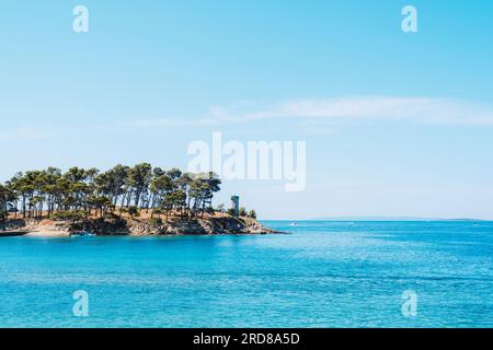 Petite île rocheuse avec phare sur la plage de Rajska sur l'île de Rab en Croatie. Banque D'Images