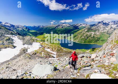 Randonneur marchant sur la crête de montagne au-dessus du lac bleu Montespluga, Madesimo, Valle Spluga, Valtellina, Lombardie, Italie, Europe Banque D'Images