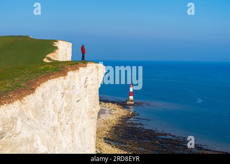 Le touriste se dresse au sommet de la falaise surplombant le phare de Beachy Head, les falaises de craie Seven Sisters, le parc national de South Downs, East Sussex, Angleterre Banque D'Images