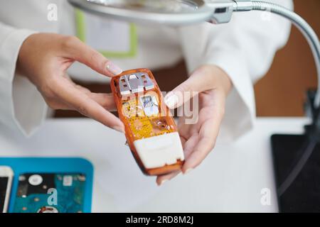 Téléphone de fonction démonté dans les mains d'une femme réparatrice Banque D'Images