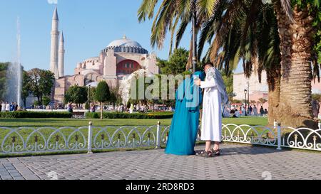 Un couple en robe traditionnelle profitant du parc Sultanahmet sur une soirée d'été avec la mosquée Sainte-Sophie derrière, Istanbul, Turquie Banque D'Images