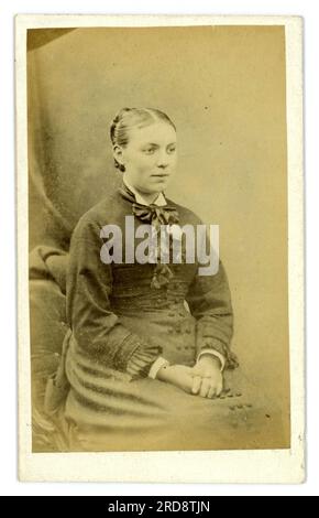 Original victorien CDV (carte de visite ou carte de visite) d'une jolie jeune femme assise, portant une robe avec une petite agitation sur sa robe, de l'atelier d'Edouard Nickels 75 Duke Street, Chelmsford, Essex, Angleterre, Royaume-Uni vers 1879. Banque D'Images