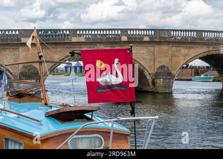 19 juillet 2023. Les bateaux participant à l'événement annuel Swan Upping sur la Tamise ont atteint la ville de Henley-on-Thames dans l'Oxfordshire, en Angleterre, au Royaume-Uni, aujourd'hui. Le drapeau de Swan du Thames Vintage Boat Club vole à un lancement avec Henley Bridge en arrière-plan. Banque D'Images