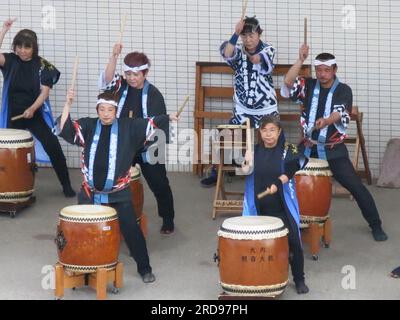 Un groupe de batteurs japonais en costume traditionnel jouent de leur batterie sur le quai du port de Shimizu comme adieu pour un bateau de croisière en visite. Banque D'Images