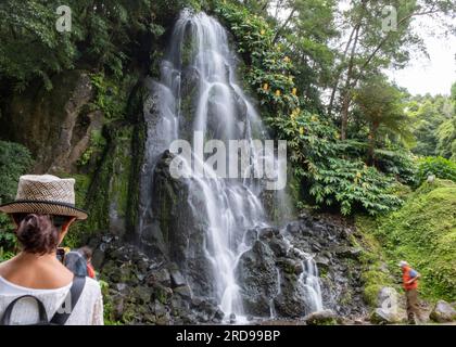 Cascade dans le jardin botanique de Ribeira do Guilherme dans le Nordeste avec des touristes, île Sao Miguel aux Açores. Banque D'Images