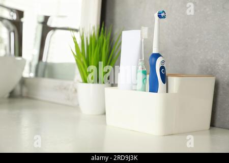 Brosses à dents électriques et tube de pâte sur comptoir blanc dans la salle de bain. Espace pour le texte Banque D'Images
