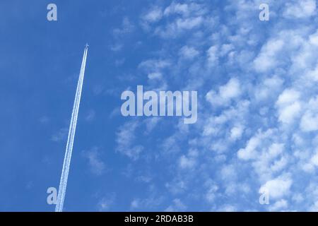 Un avion de ligne international de passagers quitte un contrail à haute altitude de particules de glace à environ 30000 pieds. Il passe sur un groupe d'altocumulus. Banque D'Images