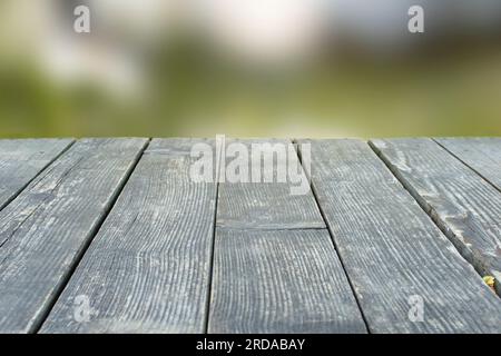 vieille table de planches de bois avec fond d'herbe verte défocalisé, mise au point douce en gros plan, texture abstraite pour le placement de produit Banque D'Images