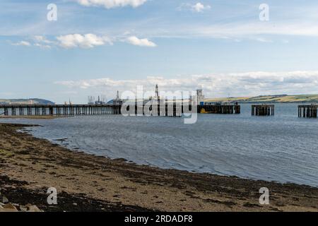 Quais d'amarrage en bois à Invergordon avec plate-forme de forage pétrolier et plates-formes en arrière-plan. Banque D'Images