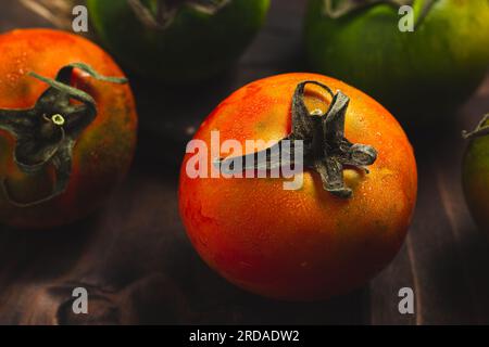 Collection de tomates entières colorées servies sur un fond rustique en bois, tomatos nature morte Banque D'Images