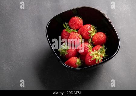 photo fraise juteuse couchée dans une assiette sur un fond gris vue de dessus Banque D'Images