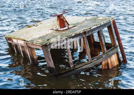 Une épave de navire coulé repose au fond d'un port paisible, sa coque scintillant dans la mer ensoleillée. Banque D'Images