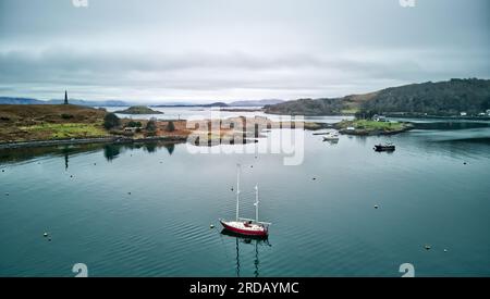 Un yacht est amarré dans la baie d'Ardantrive, avec le monument de Hutcheson sur Kerrera sur la gauche et le château de Dunollie sur la droite Banque D'Images