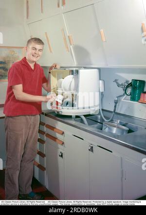 Cuisine dans le passé. Un jeune homme de la société suédoise Electrolux premier lave-vaisselle, le lave-vaisselle de paillasse D10, a appelé le pot rond ou boîte ronde, qui a commencé la production en 1959, et a ensuite coûté 410 SEK plus TVA. Le lave-vaisselle a été produit jusqu'en 1973 et a été produit à 50 000 exemplaires. La grande différence avec les lave-vaisselle modernes était que les paniers à cordes avec les assiettes et les verres sales tournaient à l'intérieur et étaient lavés propres par des jets d'eau stationnaires. Suède 1959. Conard Banque D'Images