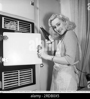 Ullacarin Rydén. 1926-1974. Actrice suédoise. Ici dans son appartement le 3 février 1951, où elle se tient près de son petit réfrigérateur typique de l'époque et a sorti une bouteille de bière des brasseries Aktiebolaget Stockholm. Suède 1951. Conard réf. 1613 Banque D'Images