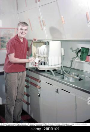 Cuisine dans le passé. Un jeune homme de la société suédoise Electrolux premier lave-vaisselle, le lave-vaisselle de paillasse D10, a appelé le pot rond ou boîte ronde, qui a commencé la production en 1959, et a ensuite coûté 410 SEK plus TVA. Le lave-vaisselle a été produit jusqu'en 1973 et a été produit à 50 000 exemplaires. La grande différence avec les lave-vaisselle modernes était que les paniers à cordes avec les assiettes et les verres sales tournaient à l'intérieur et étaient lavés propres par des jets d'eau stationnaires. Suède 1959. Conard Banque D'Images