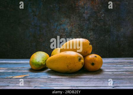 Groupe de mangues mûres dans un environnement sombre sur une table en bois. Vue latérale. Banque D'Images