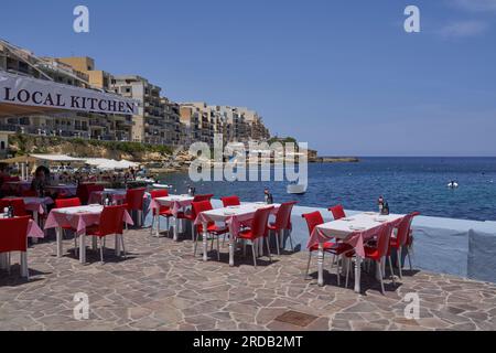 Tables et chaises de restaurant installées sur le front de mer de Marsalforn sur la côte de Gozo à Malte Banque D'Images
