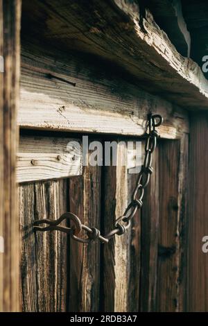 Une vieille porte en bois texturé vintage avec chaîne en fonte utilisée pour la serrure. Uttarakhand, Inde. Banque D'Images