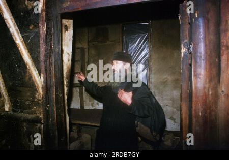 Monastère de Tarcau, comté de Neamt, Roumanie, 1999. Moine dans une cellule monastique en bois endommagée par le feu. Banque D'Images