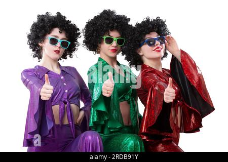 Filles de style disco dans des costumes évasés colorés et perruques afro-américaines sur un fond blanc. Style années 70 ou 80. Banque D'Images