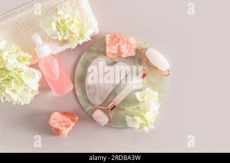 un ensemble de cosmétiques et un rouleau pour le massage, un grattoir gua sha pour le soin de la peau du visage, du cou et de la zone décalte. Vue de dessus. pastel Banque D'Images