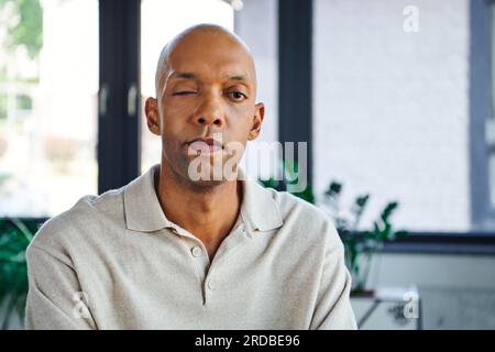 des clichés professionnels, un homme à la peau foncée et audacieux atteint de myasthénie grave regardant la caméra, un employé de bureau afro-américain atteint d'un syndrome de ptose oculaire Banque D'Images