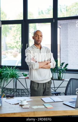 headshots professionnels, homme d'affaires afro-américain avec syndrome des yeux regardant la caméra et debout avec les bras pliés, myasthénie gravis, peau foncée Banque D'Images