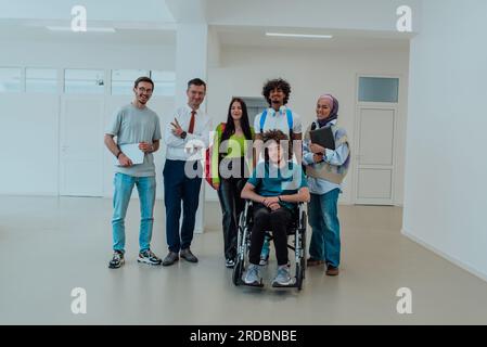 Un groupe d'étudiants avec un professeur et un collègue en fauteuil roulant se tiennent ensemble dans le couloir d'une université moderne Banque D'Images