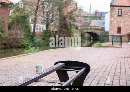 Une tasse usagée dans un endroit fréquenté par de nombreux dormeurs rudes le long de la rivière Foss, York. Sans-abri dans les rues de York. Yorkhire, Royaume-Uni. Banque D'Images