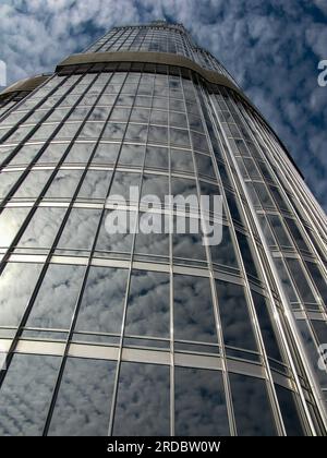 view of the burj khalifa from the observation platform on a background of blue sky with clouds reflected in the glass windows of a skyscraper, Dubai, Stock Photo