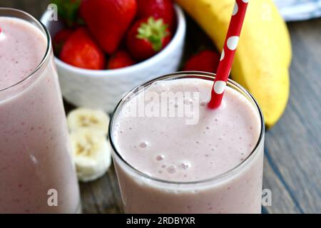 Smoothie banane fraise dans un verre transparent sur une table en bois Banque D'Images