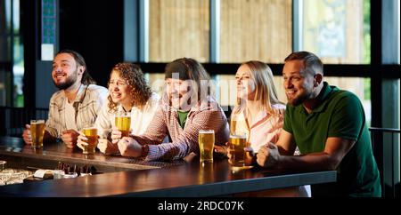 Des gens joyeux, des amis assis dans le bar, regardant attentivement la traduction de match de football, boire, ing bière, s'amuser Banque D'Images