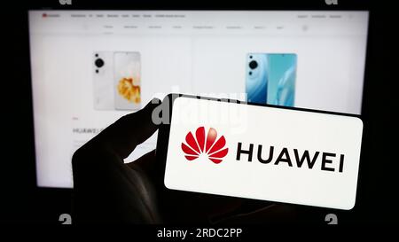 Personne tenant le smartphone avec le logo de la société chinoise Huawei technologies Co. Ltd. Sur l'écran en face du site Web. Concentrez-vous sur l'affichage du téléphone. Banque D'Images