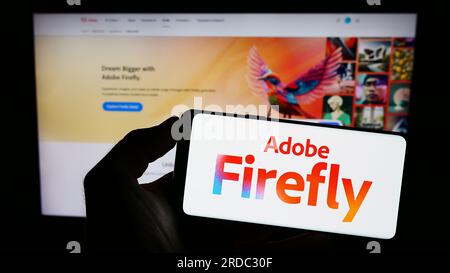 Personne tenant le smartphone avec le logo du produit d'IA générative Adobe Firefly sur l'écran en face du site Web. Concentrez-vous sur l'affichage du téléphone. Banque D'Images