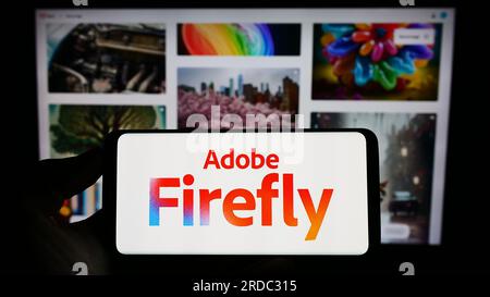 Personne tenant le téléphone portable avec le logo du produit d'IA générative Adobe Firefly sur l'écran en face de la page Web de l'entreprise. Concentrez-vous sur l'affichage du téléphone. Banque D'Images