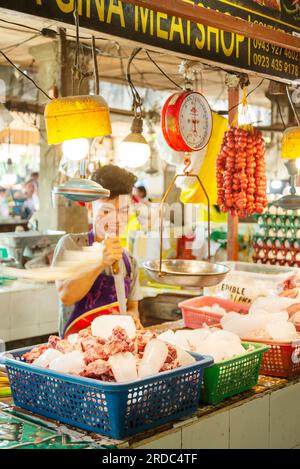 Île de Cebu, Philippines-27 janvier 2023 : en utilisant l'extrémité pointue d'une lame de coupe de viande, l'homme brise la glace, pour mélanger avec du porc cru mea Banque D'Images