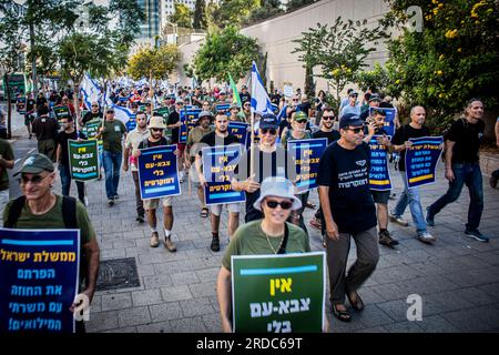 Tel Aviv, Israël. 19 juillet 2023. Les réservistes israéliens tiennent des pancartes qui indiquent en hébreu "il y a maintenant une armée populaire sans démocratie (L) et "le gouvernement d'Israël vous avez rompu le contrat avec les soldats de réserve" lors d'une manifestation à tel Aviv. Un plan controversé du gouvernement visant à réformer le système judiciaire du pays a brisé de profondes divisions au sein de la société israélienne. Ces divisions ont infiltré les forces armées, où les réservistes des unités stratégiques clés se sont engagés à ne pas se présenter à la réserve si les changements législatifs sont poussés à adopter. Crédit : SOPA Images Limited/Alamy Live News Banque D'Images